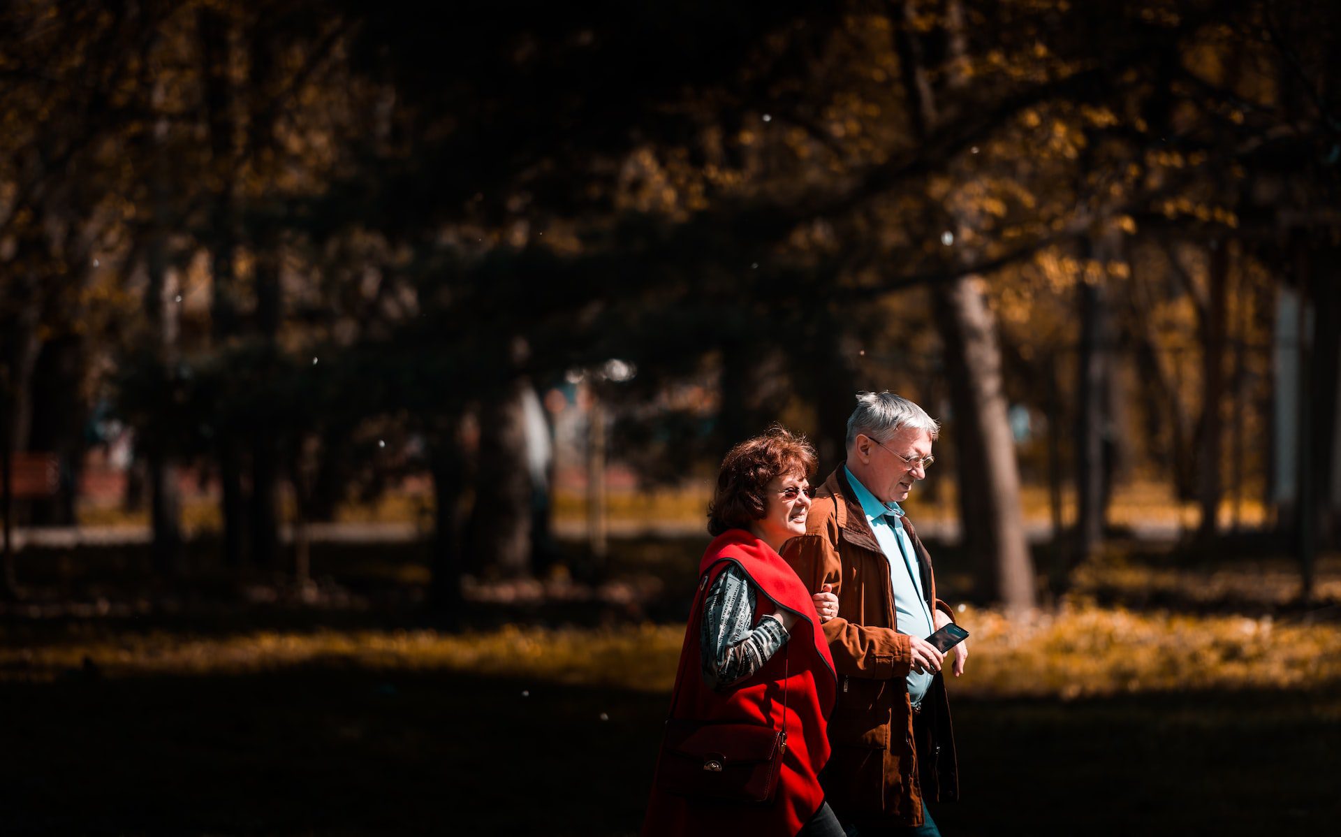 couple walking through a park in the fall